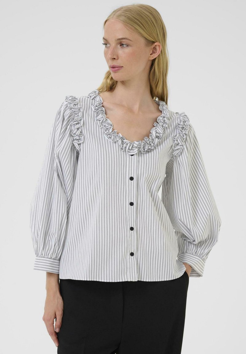 Striped blouse in white and black with ruffled neckline, long balloon sleeves, and black buttons down the front. Cotton material.