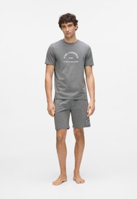 Hall halli lühikeste varrukatega T-särk ja sobivad lühikesed püksid, valmistatud pehmest kangast, millel on valged trükitud tekstid ja korralikud õmblused, paljajalu seljas.