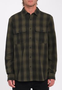 Grønne og sorte ternede skjorte med knaplukning, lavet af flannel, med to brystlommer og lige kant. Har knaplukning og lange ærmer.
