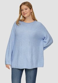 Hellblauer Strickpullover mit strukturiertem Muster, Rundhalsausschnitt und oversize Passform. Weicher Stoff und lange Ärmel. Kombiniert mit blauen Jeans.