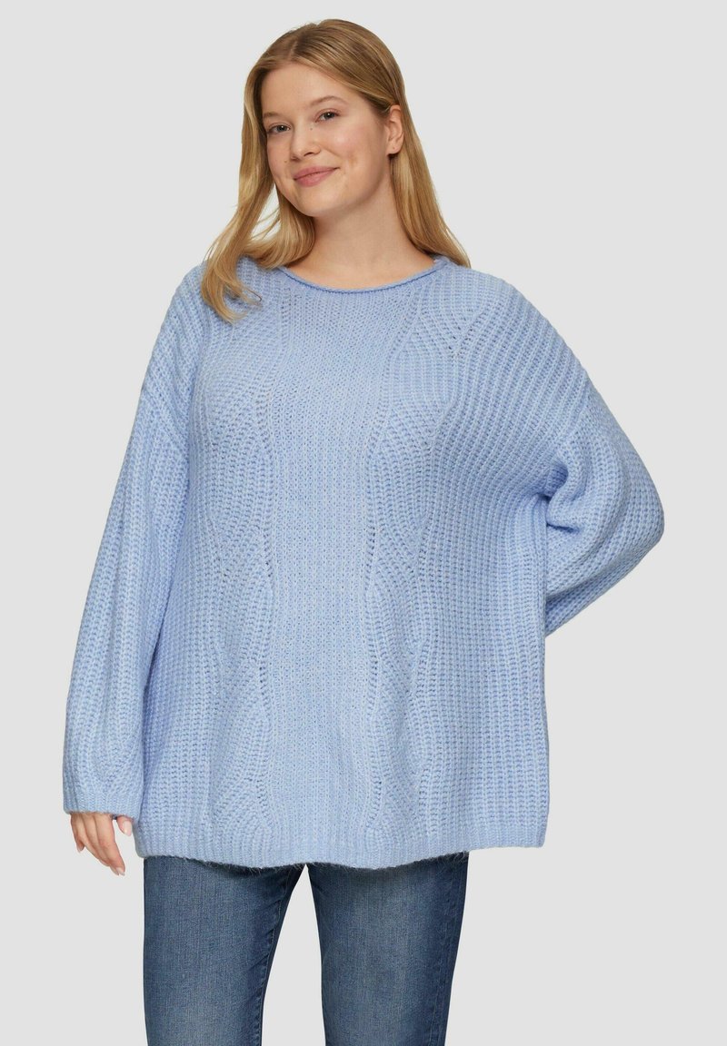 Hellblauer Strickpullover mit strukturiertem Muster, Rundhalsausschnitt und oversize Passform. Weicher Stoff und lange Ärmel. Kombiniert mit blauen Jeans.