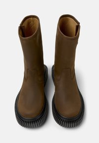 Bruna läderstövlar med en slät yta, rund tå, slip-on design och en tjock svart gummisula med ett räfflat mönster.
