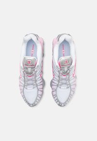 Nike Shox Sneakers in Weiß mit pinken Akzenten. Mit einem strukturierten Obermaterial, grauem Schnürsystem und gepolsteter Sohle für Unterstützung.
