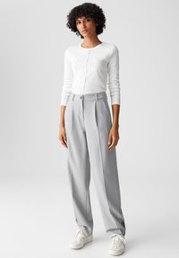 White fitted long-sleeve top, gray pleated trousers with a button, and white sneakers. Minimalist design, soft texture, and neutral colors.