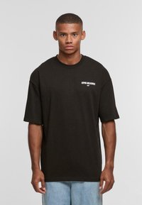 Black cotton t-shirt with short sleeves, a crew neck, and white text reading "ASPIRE AND ACHIEVE" on the left chest. Casual fit.