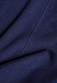 Tissu bleu marine avec une texture côtelée, présentant une surface douce et lisse. Le matériau semble flexible et léger avec des accents de coutures visibles.