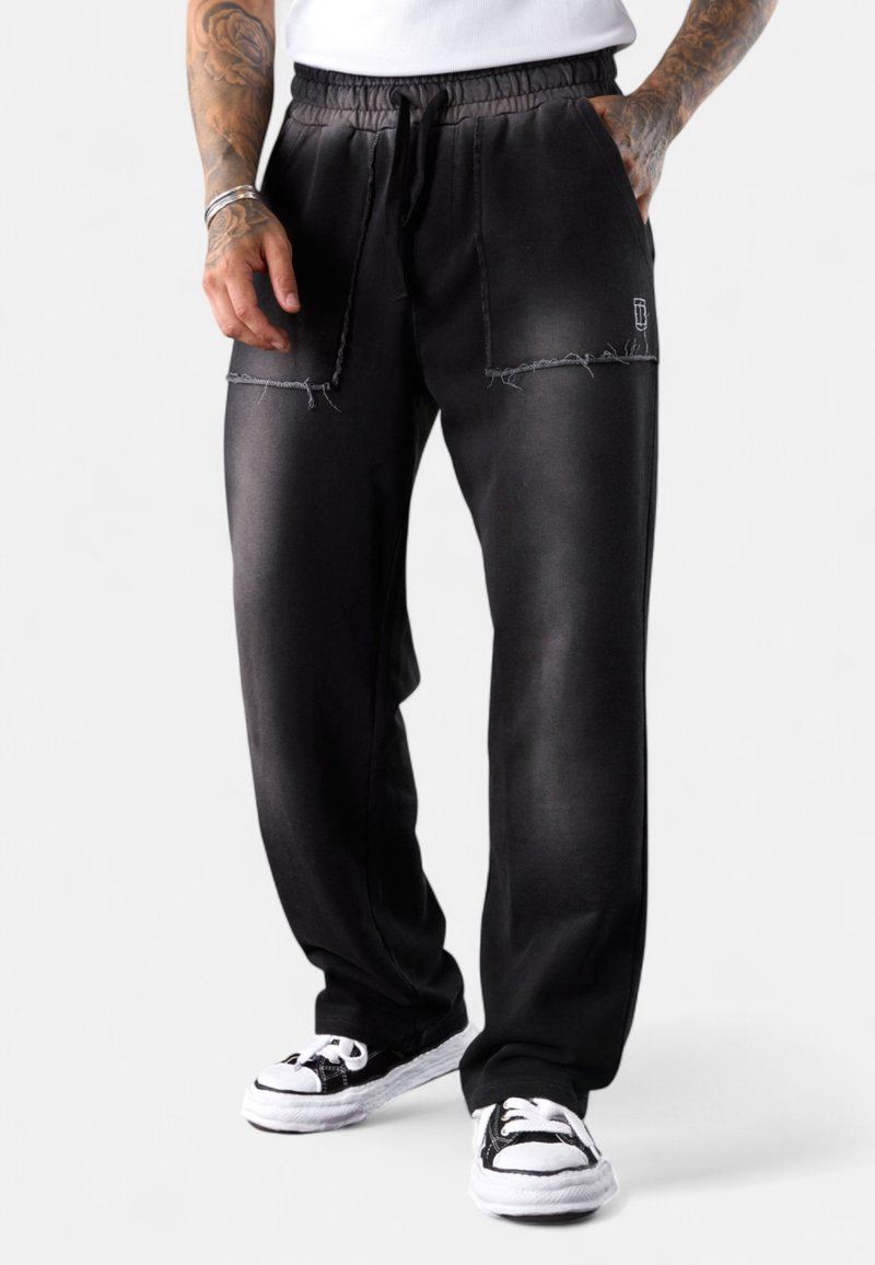 Schwarze Sweatpants mit einem lockeren Schnitt, mit elastischem Bund und Kordelzug. Mit abgetragenen Details und dezentem Markenlogo auf der Vorderseite.