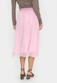 Gonna midi semi-trasparente rosa con vita elastica e design fluido a strati. Scarpe con stampa animale e tacchi a blocco robusti.