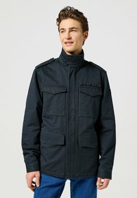 Marineblaues Militärjacke mit hohem Kragen, zwei Brusttaschen und zwei unteren Taschen. Verfügt über Schulterklappen und eine glatte Textur.