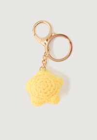 Yellow crocheted star keychain attached to a gold keyring with a lobster clasp on a white background.