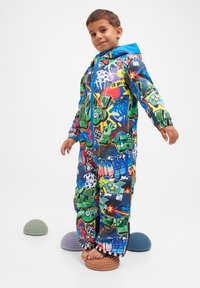 Färgglad snönsuit med graffiti-mönster och en blå huva, elastiska ärmslut och dragkedjestängning, med gröna och flerfärgade mönster.