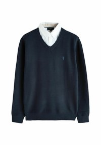 Navyblauwe V-hals trui over een wit overhemd met knopen, met een klein geborduurd logo op de linkerborst.