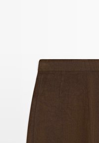 Gonna marrone a vita alta con una cintura piatta e sottili cuciture verticali su uno sfondo bianco uniforme.