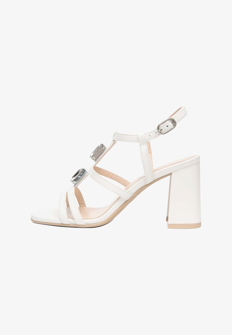 Sandale blanche à talon avec bride de cheville ajustable, deux grosses pierres rectangulaires sur les brides, et talon bloc sur fond blanc.