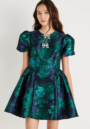 Short-sleeve dress in navy satin, featuring green floral patterns, a fitted waist, and two decorative bows at the neckline.