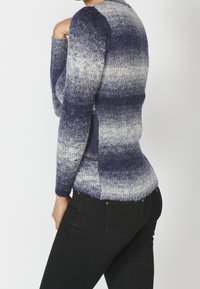 Stickad tröja med en gradientdesign från blått till grått, långa ärmar, ribbad textur och figurnära passform, bärs med svarta jeans.