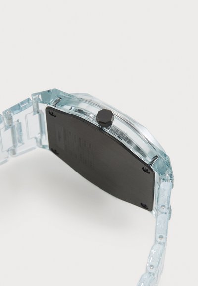 Reloj de plástico azul transparente con una parte posterior negra y corona hexagonal. Presenta una correa de eslabones transparente y tornillos visibles.