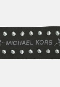 Nastro di stoffa nero con borchie argentate, con la scritta "MICHAEL KORS" in testo grigio. La texture è liscia con una finitura opaca.