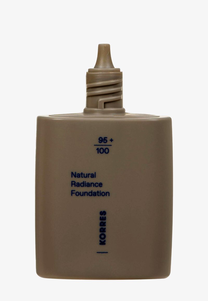 Bouteille carrée beige avec un embout effilé, étiquetée "Fond de teint Éclat Naturel" et "Korres" en texte bleu, capacité 95/100.
