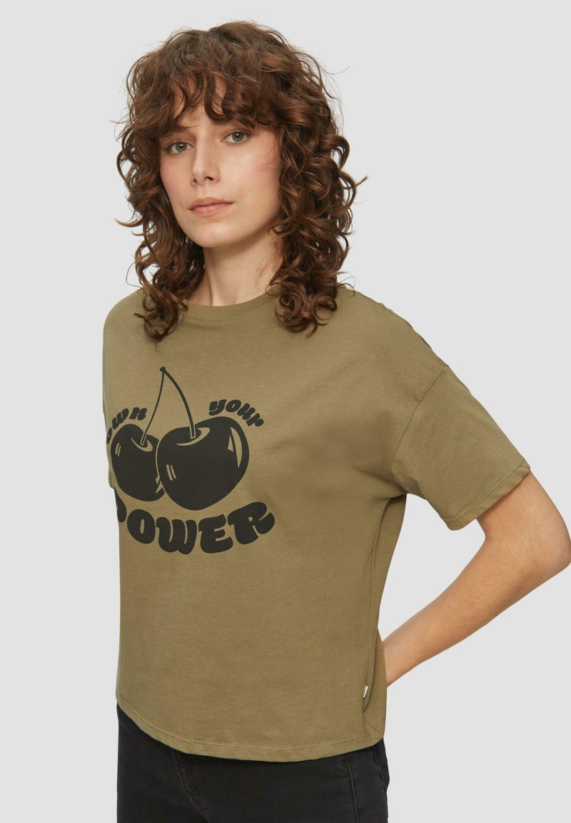 Olijfgroene katoenen t-shirt met een relaxte pasvorm, voorzien van een zwarte kersengrafiek en vetgedrukte tekst waarop "POWER" staat aan de voorkant.