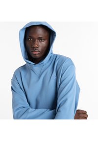 Sudadera con capucha azul claro con un acabado texturizado. Presenta un bolsillo frontal tipo canguro y un logo bordado en el pecho.