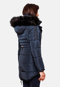 Mörkblå puffjacka med fuskpälsfodrad huva, frontdragkedja och stitchad paneldesign. Justerbar dragsko vid nederkanten.