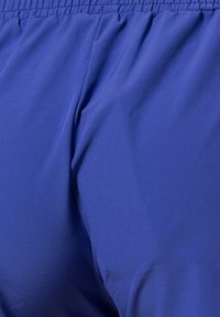 Gros plan d'un pantalon à taille élastique bleue montrant la texture du tissu et les détails des coutures.
