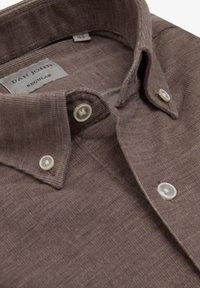 Camisa marrón de botones, con tejido texturizado, cuello estructurado y dos botones decorativos en el cuello. La etiqueta dice "DAN JOHN REGULAR."