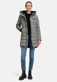 Polstret grå frakke med hætte, kviltet design, sort for, frontlynlås og knaplukning samt sidelommer; båret over en sort bluse og blå jeans.