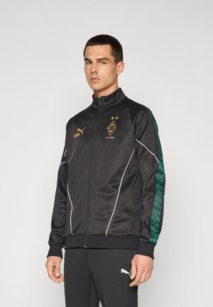 Black athletic jacket with white accents, half zip, featuring green patterned side panels and a logo with gold details.