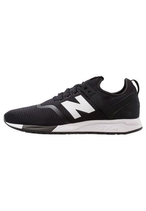 Baskets athlétiques noir et blanc avec tige en mesh, fermeture à lacets, semelle rembourrée et grand logo blanc sur le côté.