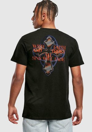 T-shirt en coton noir avec un grand graphisme au dos. Le texte en rouge gras indique "AVEC FOI ET CONFIANCE, TOUS LES PÉCHÉS FANGUERONT", accentué par un design de croix.