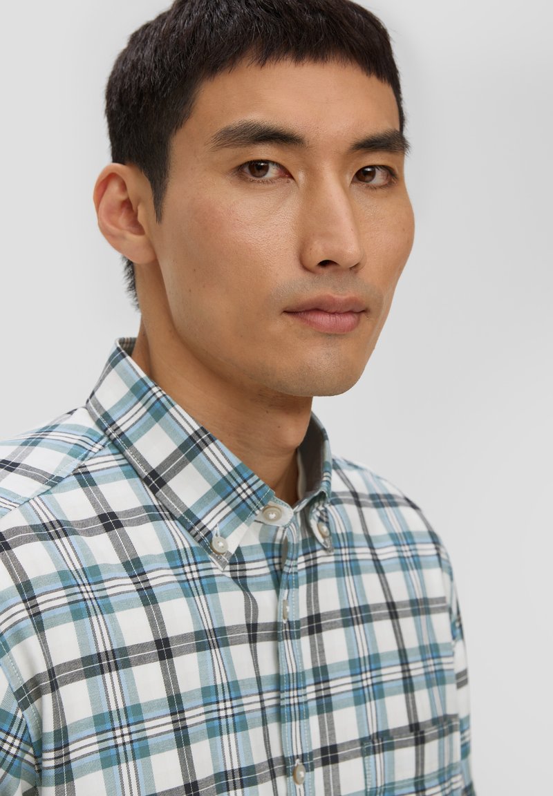 Chemise à carreaux en coton. Motif en tartan bleu, noir et blanc avec un col classique et des boutons en nacre.