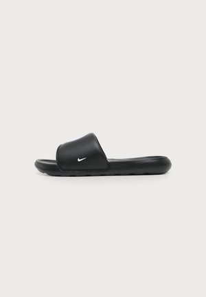 Sandalia tipo slide de Nike negra con una correa ancha y el logo blanco de Nike swoosh en el lateral, mostrada desde el lateral sobre un fondo liso.