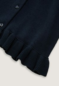 Cardigan bleumarin cu textură tricotată în formă de inimă, având un tiv ondulat și nasturi în formă de inimă pentru închidere.