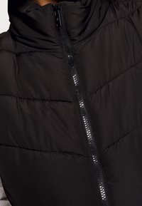 Černá péřová bunda s vysokým límcem, s horizontálními prošívanými liniemi, středním zipem a hladkou texturou látky.