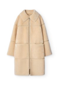 Kort beige fuskpälsjacka med krage, hel dragkedja framtill, trekvartsärmar och en blockig, quiltad design. Mjuk, plyschig textur.