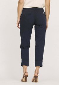 Pantalon cropped bleu marine avec une texture lisse, comportant deux poches arrière, des ourlets roulés et une ceinture pour le confort.