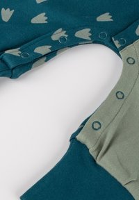 Teal bodysuit with light green accents, featuring small leaf patterns and snap closures along the side for easy dressing.