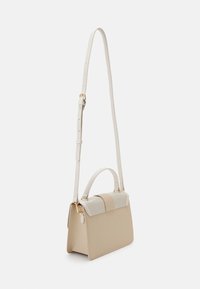 Sac à main structuré beige et blanc avec poignée supérieure et longue bandoulière réglable, présenté sur un fond blanc.