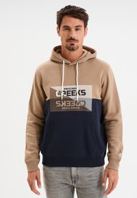 Felpa con cappuccio beige e blu navy con tasca frontale. Dotata di un logo stampato e di un design geometrico in argento metallizzato. Tessuto misto cotone.