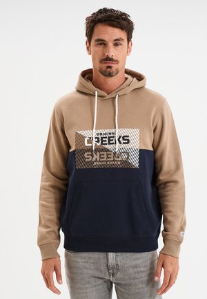Sudadera con capucha en beige y azul marino con un bolsillo frontal. Presenta un logo impreso y un diseño geométrico en plateado metálico. Tejido de mezcla de algodón.