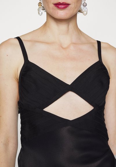 Fekete ruha, textúrázott pántokkal, keresztbe kidolgozással és kivágott részlettel. Simító selyem anyag, testhez simuló szabással.