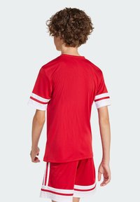 Rotes Sporttrikot mit weißen Streifen an den Ärmeln, aus leichtem Material gefertigt. Das Shirt hat einen runden Halsausschnitt und ist mit passenden roten Shorts kombiniert.