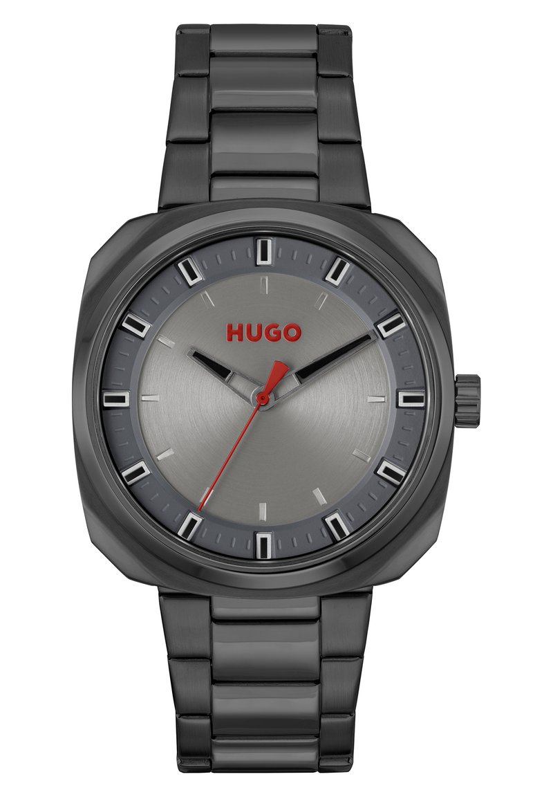 El reloj de metal negro presenta una esfera gris con marcadores de hora plateados y un logotipo rojo. Una manecilla de segundos roja en contraste complementa el diseño elegante.