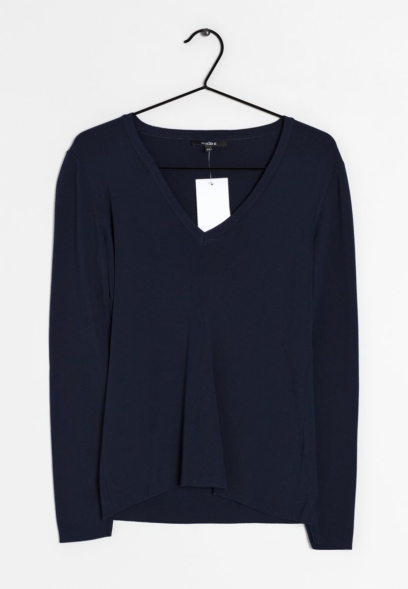 Mörkblå långärmad V-ringad tröja med avslappnad passform, med en etikett, en rundad fåll och mjukt, lätt tyg. Hänger på en svart krok.