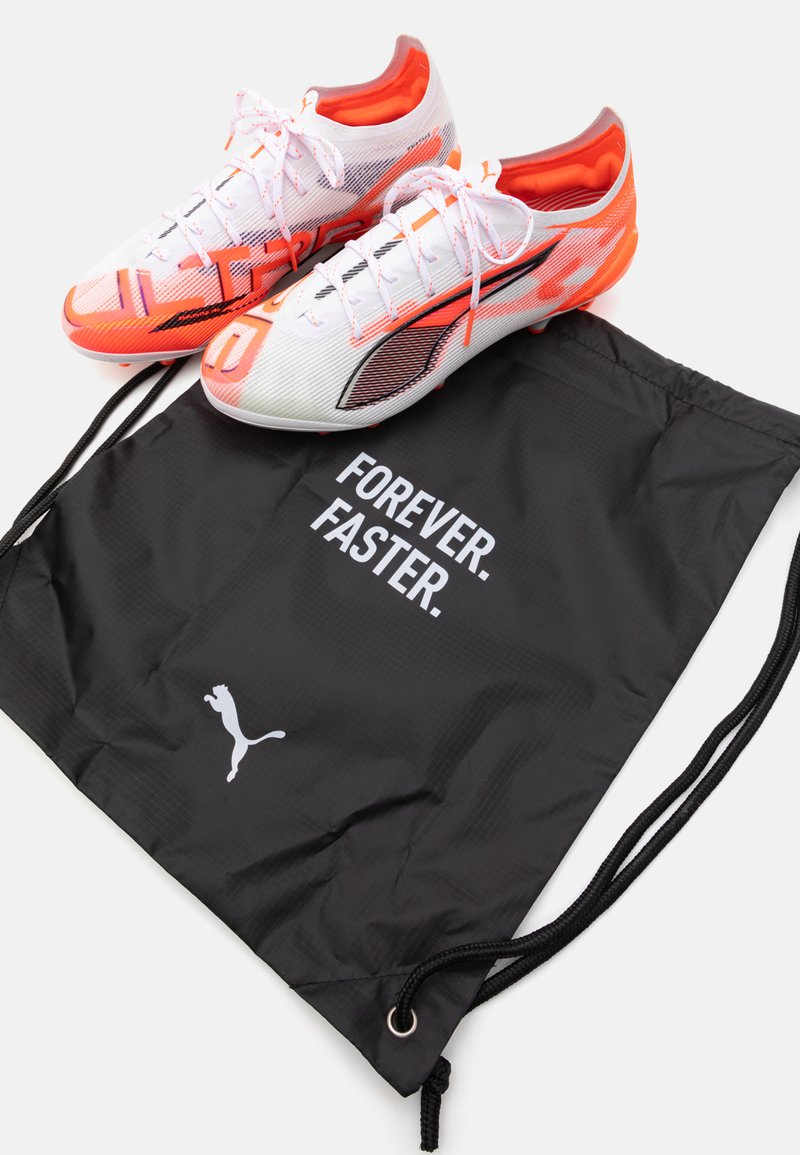 Scarpini da calcio bianchi e arancioni con un design elegante e tessuto in rete. Includono un sacchetto con cordino nero con il testo "FOREVER. FASTER." e logo.