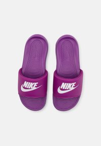 Sandales à glissière Nike violettes avec une semelle intérieure Texturée et une large sangle présentant un logo blanc bien en vue. Matériau en caoutchouc lisse tout au long.