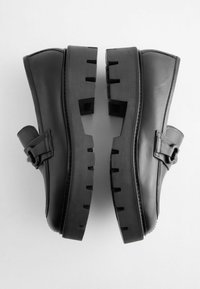 Scarpe platform in pelle nera con tomaia liscia, suola in gomma spessa con ritagli rettangolari e una fibbia decorativa di lato.