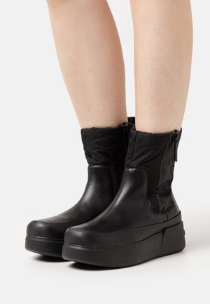 Sorte læder ankelstøvler med quiltet stofkant, sidelukninger og solide platformsåler. Glat tekstur med subtile designdetaljer.